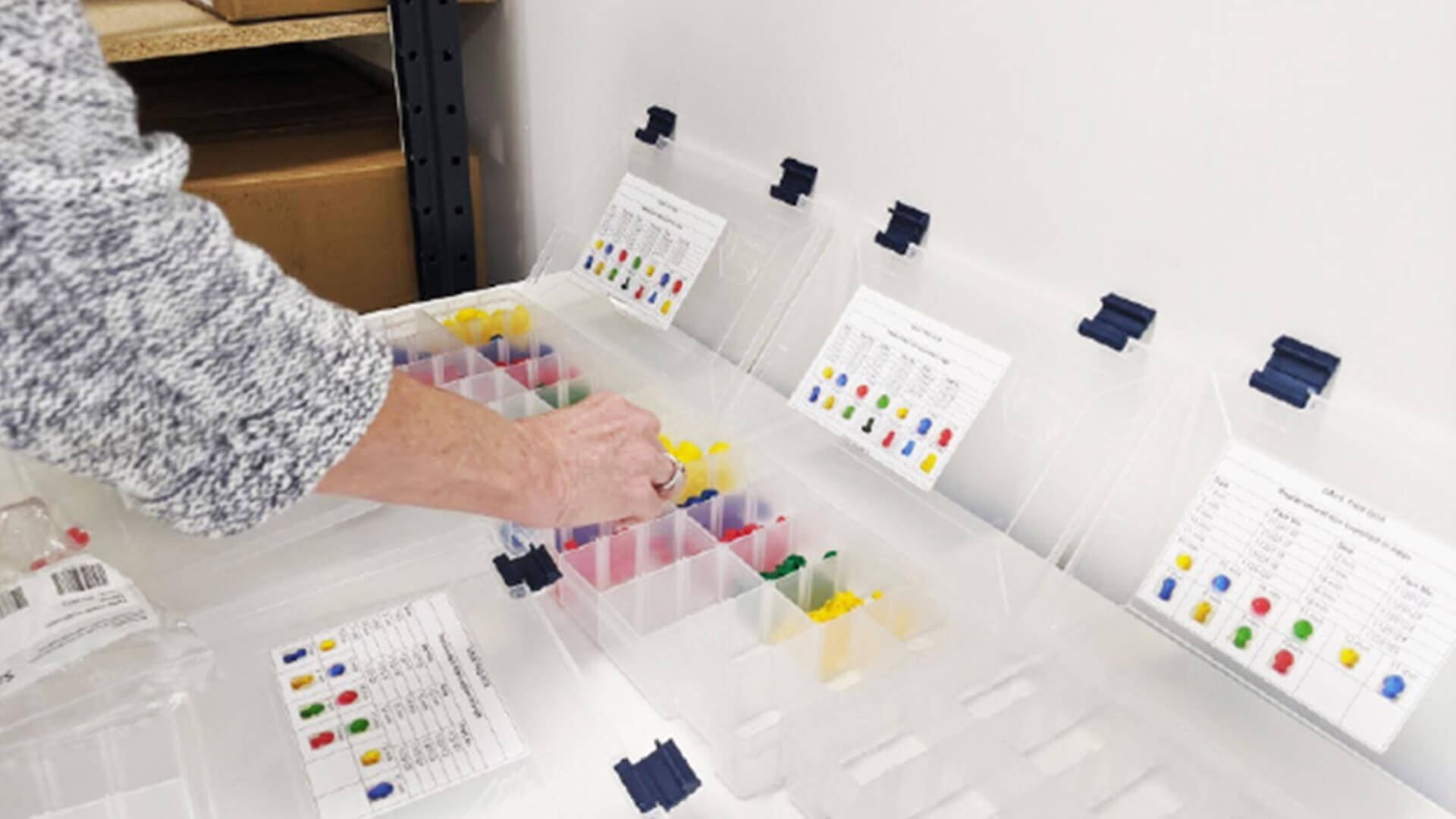 Hand reaching for colorful consumables lying in transparent boxes